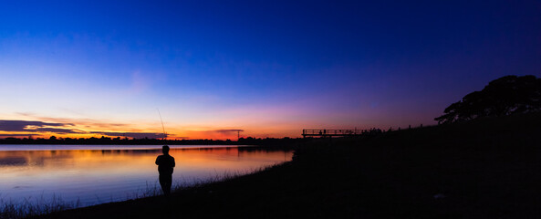 Silhouette people at the waterfront with a sunset background