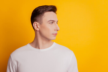 Portrait of masculine charming guy look side empty space on yellow background