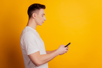 Profile portrait of young charming businessman hold phone chatting on yellow background
