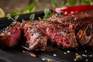Closeup of juicy beef steak slices with greens and red pepper