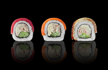 Three sushi rolls with salmon, tuna and eel on black background