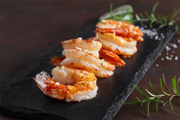 Roasted prawn tails on black slate board with rosemary