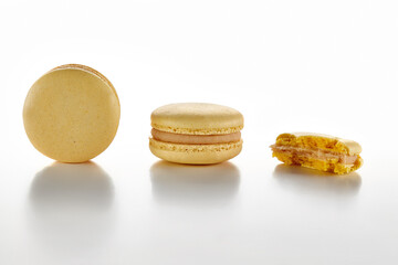 Two whole and one bitten macarons on white surface