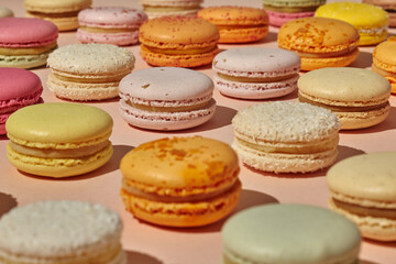 Colorful French macarons on light pink surface
