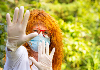 Portrait of a redhead woman wearing a medical mask and gloves