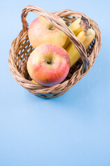 Closeup of fresh tasty organic bananas with an apple on a blue background © Giordano Trabucchi/Wirestock