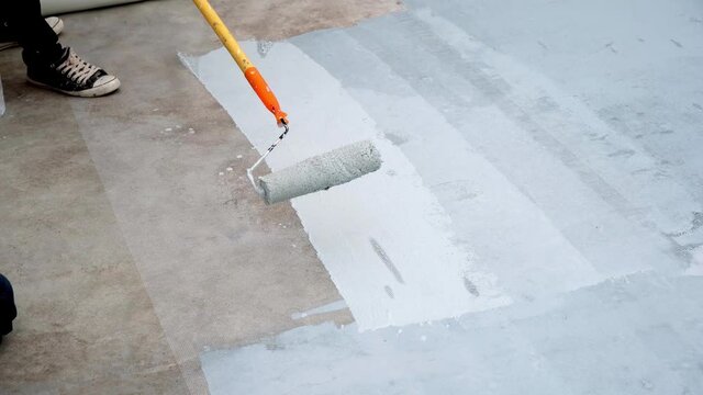Hand painted gray flooring with paint rollers for waterproof, reinforcing net,Repairing waterproofing deck flooring. Selective focus.	
