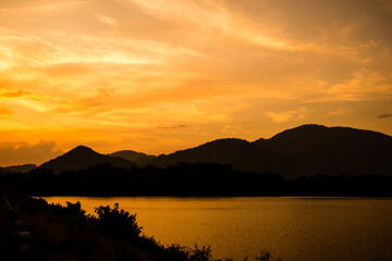 silhouette mountain with attractive background, sunset with vivid yellow sky and lake