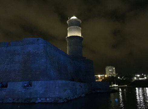 View at night of the Fort Saint Jean with the large round Tour du Fanal tower, one of the most visited monuments in Marseille. It is connected to the former port by a footbridge.