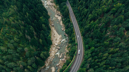 Fototapeta premium Beautiful aerial view of the road with mountains and forest, road and river, shot from above, carpathians, Ukraine