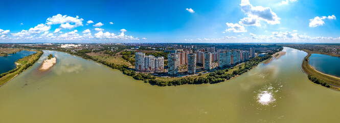 the Kuban river and a large microdistrict of the city of Krasnodar with high multi-storey buildings - a large panorama landscape on a summer day - obrazy, fototapety, plakaty