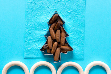 wooden beads arranged inside a christmas cookie cutter with rings on a blue paper background