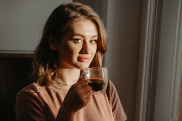 girl drinks coffee by the window
