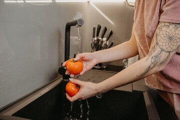 girl washes tomatoes under the tap
