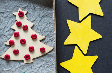 christmas tree with red beads in a cardboard box with yellow stars on gray