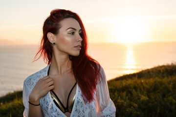 Sensual young woman standing near sea at sunset