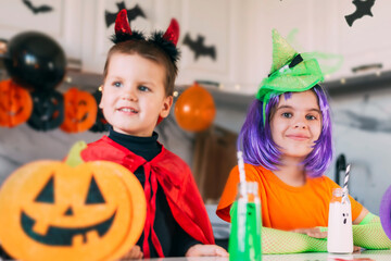 Funny toddler kids in carnival costume on Halloween party with scary drinks. Traditions, holidays, treats concept.