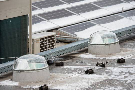 Two domes of light guides on the roof with solar panels with snow.