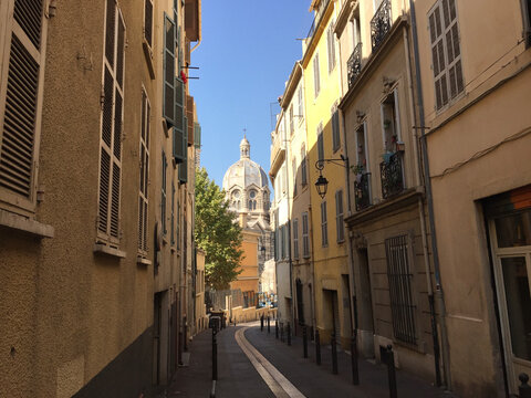 Pastel coloured residential buildings on a calm and friendly street with the Marseille Cathedral (Cath&eacute;drale de la Major) in the background, in Le Panier - Marseille's oldest neighborhood.