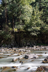 Smooth water and stones, river and wild nature, mountains, little waterfall