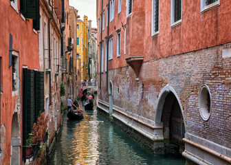 Famous waterways or rios of Venice, Italy. Gondoliers pass below bridges, tourists aboard, people crossing channel, UNESCO World heritage city.