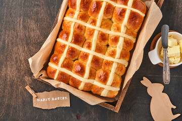 Easter Hot Cross Buns. Traditional breakfast and Easter baking holiday decorations rabbiton dark old wooden background. Bright colors, view from above on wooden table.