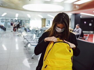 woman looking into a yellow backpack checking things airport