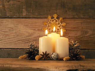 Third Advent candle burning on a rustic wooden table
