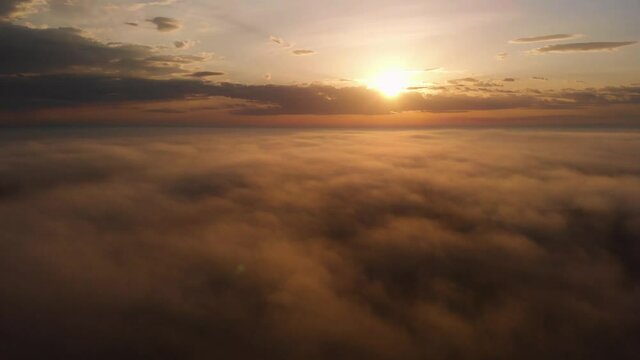 Flying over the clouds. Beautiful sunrise or sunset over the clouds. Orange sky. Beautiful sunrise landscape with morning mist. Aerial view. Colorful sky background