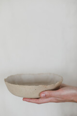 Hands holding ceramic plates isolated on white background. Minimalist set of handmade ceramic tableware and pottery