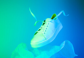 Fashion - white unisex sneakers shoe levitating on the blue and green background