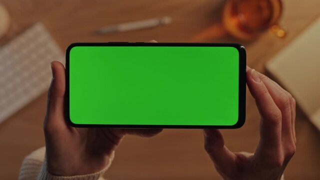 Woman tapping on green mockup screen of horizontal mobile