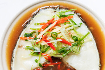 Steamed snow fish with soy sauce. Snow fish, soy sauce, ginger, scallion and chili. Top view on white table background.