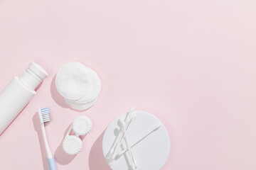 Ear sticks, cotton pads, toner (lotion) and toothbrush on pink background. Beauty and hygiene...