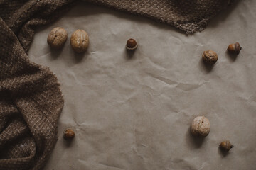 autumn theme, brown paper texture background with cozy warm plaid, walnuts and acorns, top view, copyspace