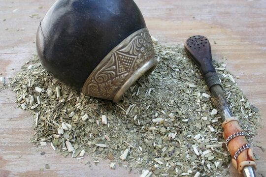 Infusi&oacute;n de yerba mate argentina y latinoamericana, con su mate o porongo y su bombilla con fondo de mesa de madera de pino desenfocado.