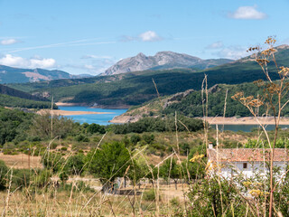 A panoramic view of the slopes and ridges of the mountains with a beautiful blue lake and a village