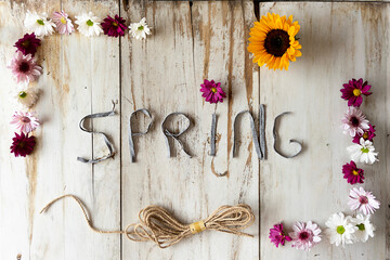 Spring beautiful rustic title with a frame full of flowers and a string on a white wooden background