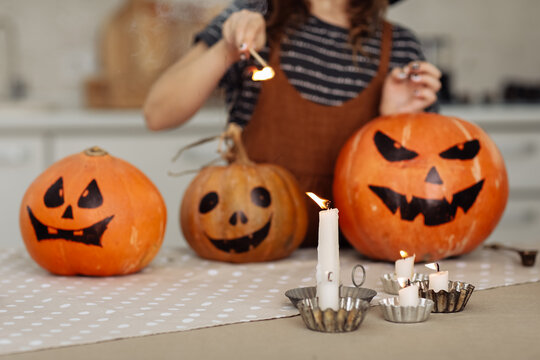 child girl lights a candle for Halloween. little girl in witch costume with carving pumpkin with a face made by child. Happy family preparing for Halloween. selective focus