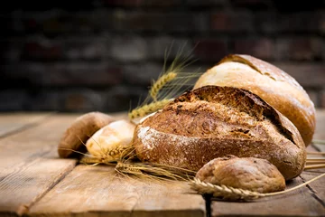 Fototapeten Brot Bäckerei Hintergrund. Set aus frisch gebackenem knusprigem Brot und Brötchen mit Weizenähren auf Holztisch mit Kopierraum  © kucherav