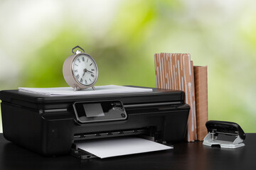 Stack of books and home printer against blurred background