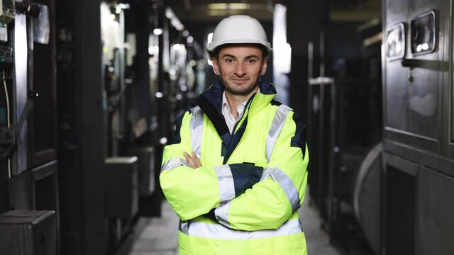 Zoom portrait of caucasian heavy industry electricity worker smiling confident for camera while coworking on construction site. High voltage power station. Electrician, electric worker.