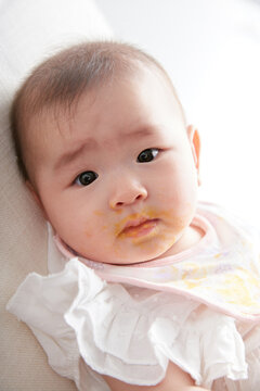 Closeup of cute Asian baby eating pumpkin puree