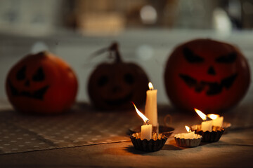 candles are burning on the table. Halloween pumpkin lantern with scary face on background. Family preparing all hallows eve Halloween party decorations. Background, copy space. selective focus
