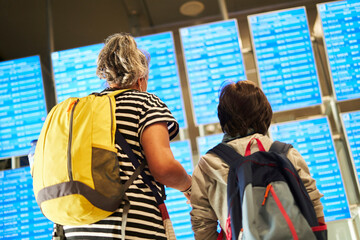 Passengers looking at the departure board in the airport terminal