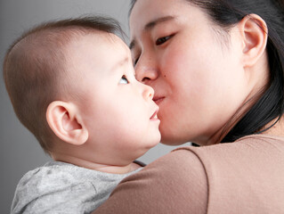 Cute Asian baby being held by mother