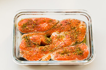 Raw trout fillet with spices in glass baking dish, top view, healthy food concept