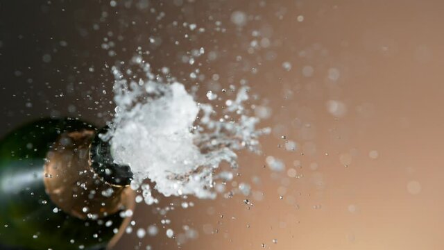Super slow motion of Champagne explosion with flying cork closure, opening champagne bottle closeup, golden bokeh glitters on background. Filmed on high speed cinematic camera at 1000 fps.