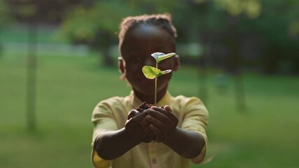 African girl showing on camera fresh green seedling