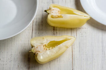 Cut in half yellow bell peppers on a light wooden background.
